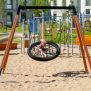 Single Swing (BNS 90cm) ayunan sarang burung dengan rangka kayu dan logam di taman bermain berpasir.